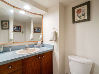 This charming bathroom features a spacious vanity with a light blue countertop, complemented by warm wooden cabinetry.