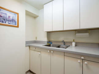 This bright and clean kitchen area features ample cabinet space for storage, both above and below the countertop.