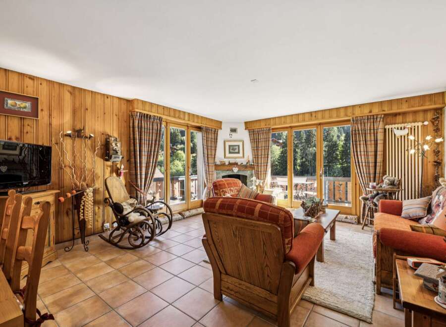 Experience cozy living in this charming mountain retreat, featuring warm wood-paneled walls and a inviting fireplace.