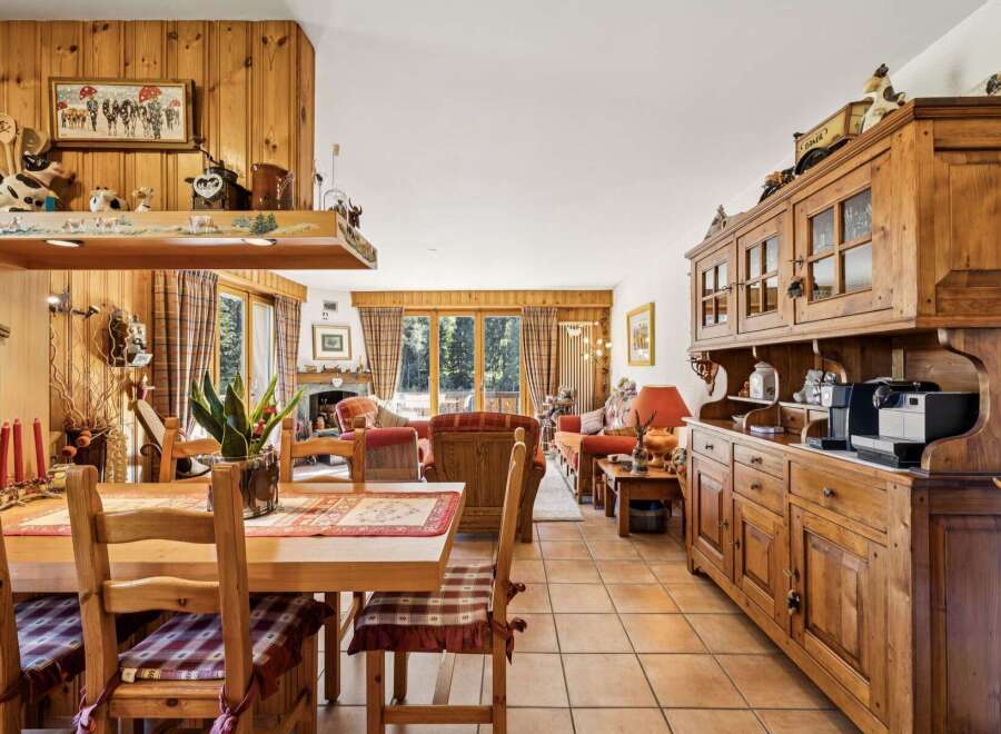 Experience rustic charm in this inviting dining and living area, featuring warm wood paneling and a cozy fireplace.