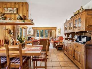 Experience rustic charm in this inviting dining and living area, featuring warm wood paneling and a cozy fireplace.
