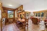 Experience cozy living in this charming mountain retreat, featuring a warm wood-paneled dining area with a large window offering stunning forest views.