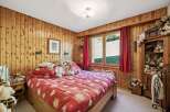 Experience cozy mountain living in this charming bedroom, featuring warm wood-paneled walls and a comfortable bed adorned with playful teddy bears.