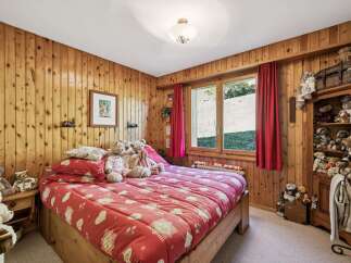 Experience cozy mountain living in this charming bedroom, featuring warm wood-paneled walls and a comfortable bed adorned with playful teddy bears.