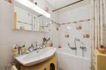 This charming bathroom features a pristine white sink with modern chrome fixtures, complemented by a collection of toothbrushes and toiletries neatly organized in yellow holders.