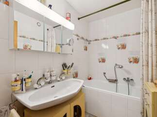 This charming bathroom features a pristine white sink with modern chrome fixtures, complemented by a collection of toothbrushes and toiletries neatly organized in yellow holders.
