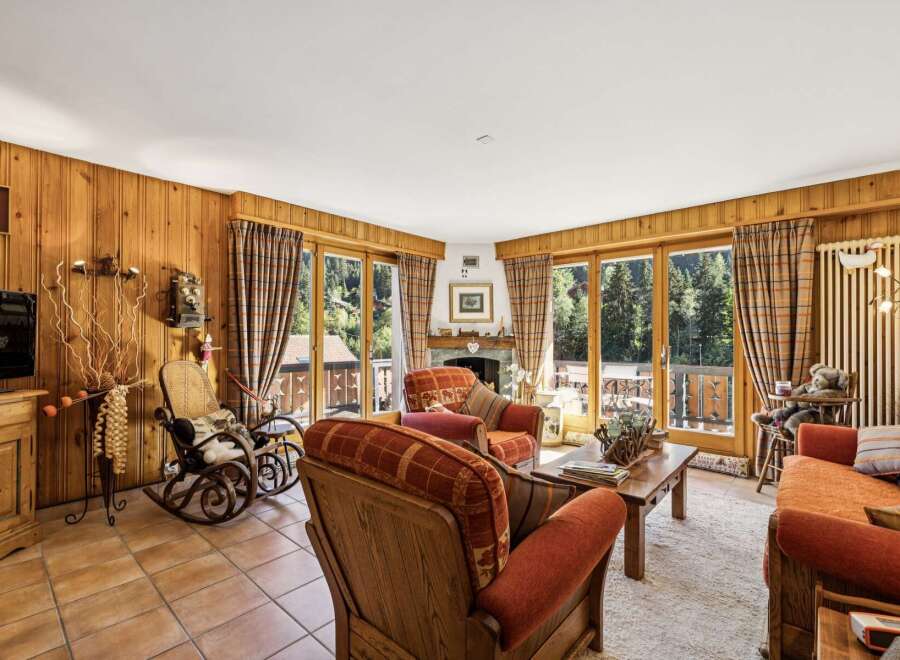 Experience cozy living in this charming mountain retreat, featuring warm wood-paneled walls and a inviting fireplace.