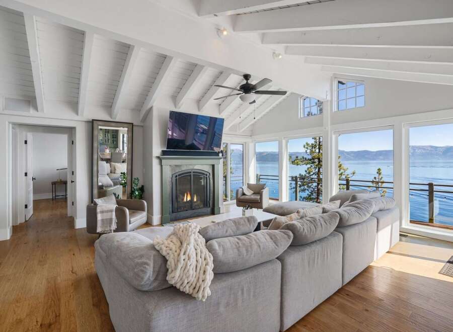 Experience breathtaking lakefront living in this stunning living room, featuring a cozy fireplace and a large sectional sofa perfect for gatherings.