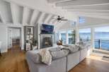 Experience breathtaking lakefront living in this stunning living room, featuring a cozy fireplace and a large sectional sofa perfect for gatherings.