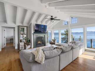Experience breathtaking lakefront living in this stunning living room, featuring a cozy fireplace and a large sectional sofa perfect for gatherings.