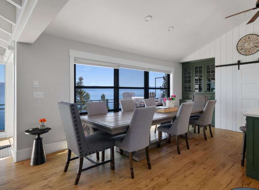Enjoy breathtaking lake views from this elegant dining room, featuring a spacious wooden table and comfortable upholstered chairs.