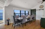 Enjoy breathtaking lake views from this elegant dining room, featuring a spacious wooden table and comfortable upholstered chairs.