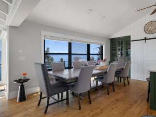Enjoy breathtaking lake views from this elegant dining room, featuring a spacious wooden table and comfortable upholstered chairs.