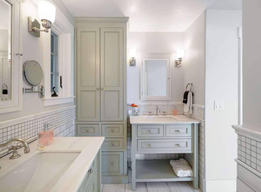 This elegant bathroom features a spacious vanity with a marble countertop and a built-in sink, complemented by a tall, light green storage cabinet.