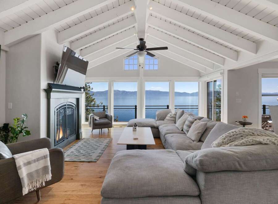 Experience breathtaking lake views from this stunning living room, featuring a cozy fireplace and a spacious sectional sofa perfect for relaxation.