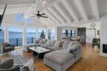 Experience breathtaking lake views from this stunning living room, featuring a spacious sectional sofa perfect for relaxation.