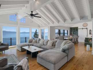 Experience breathtaking lake views from this stunning living room, featuring a spacious sectional sofa perfect for relaxation.