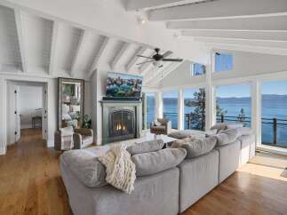 Experience breathtaking lakefront living in this stunning living room, featuring a cozy fireplace and a large sectional sofa perfect for gatherings.
