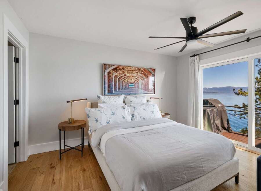 Experience breathtaking lake views from this serene bedroom, featuring a comfortable king-sized bed adorned with floral-patterned linens.