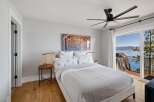 Experience breathtaking lake views from this serene bedroom, featuring a comfortable king-sized bed adorned with floral-patterned linens.