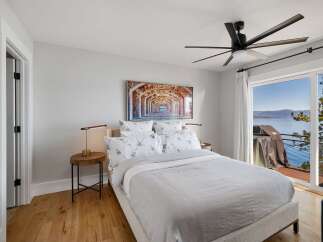 Experience breathtaking lake views from this serene bedroom, featuring a comfortable king-sized bed adorned with floral-patterned linens.