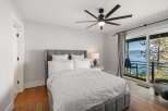 Experience breathtaking lake and mountain views from this serene bedroom, featuring a comfortable king-sized bed with plush white linens.