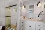 This bright and airy bathroom features a spacious glass-enclosed shower with white tiled walls and a unique mosaic tiled floor.