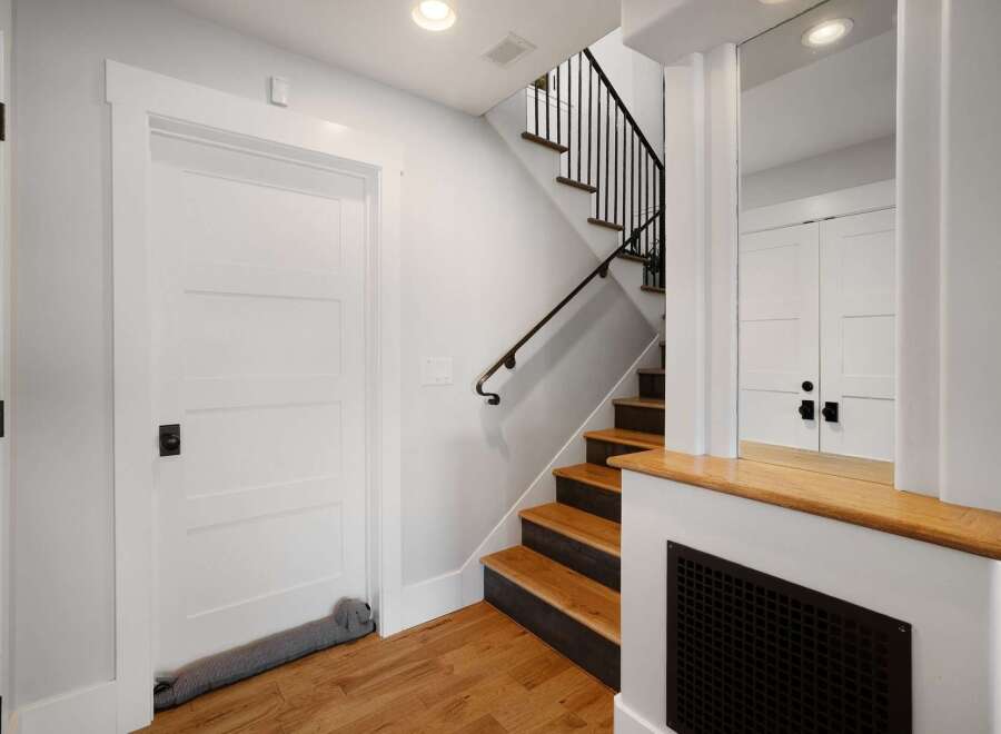 This modern entryway features a sleek white door with a stylish black knob, complemented by a charming dog-shaped draft stopper.