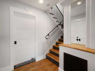 This modern entryway features a sleek white door with a stylish black knob, complemented by a charming dog-shaped draft stopper.