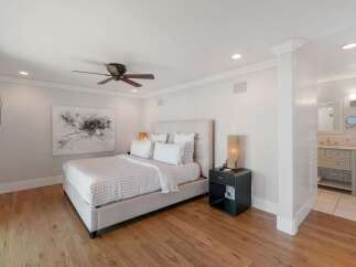Experience luxury and comfort in this beautifully appointed bedroom, featuring a plush king-size bed with crisp white linens and a striking abstract artwork above.