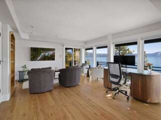 Experience breathtaking lake views from this stunning living space, featuring a dedicated home office with a modern desk and ergonomic chair.