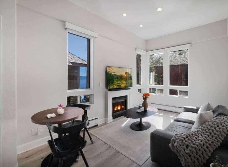 Experience breathtaking lake and mountain views from this beautifully appointed living space, featuring a cozy fireplace and a modern entertainment setup.