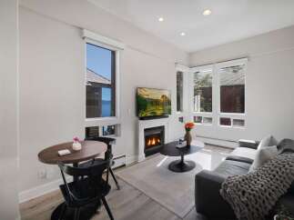 Experience breathtaking lake and mountain views from this beautifully appointed living space, featuring a cozy fireplace and a modern entertainment setup.