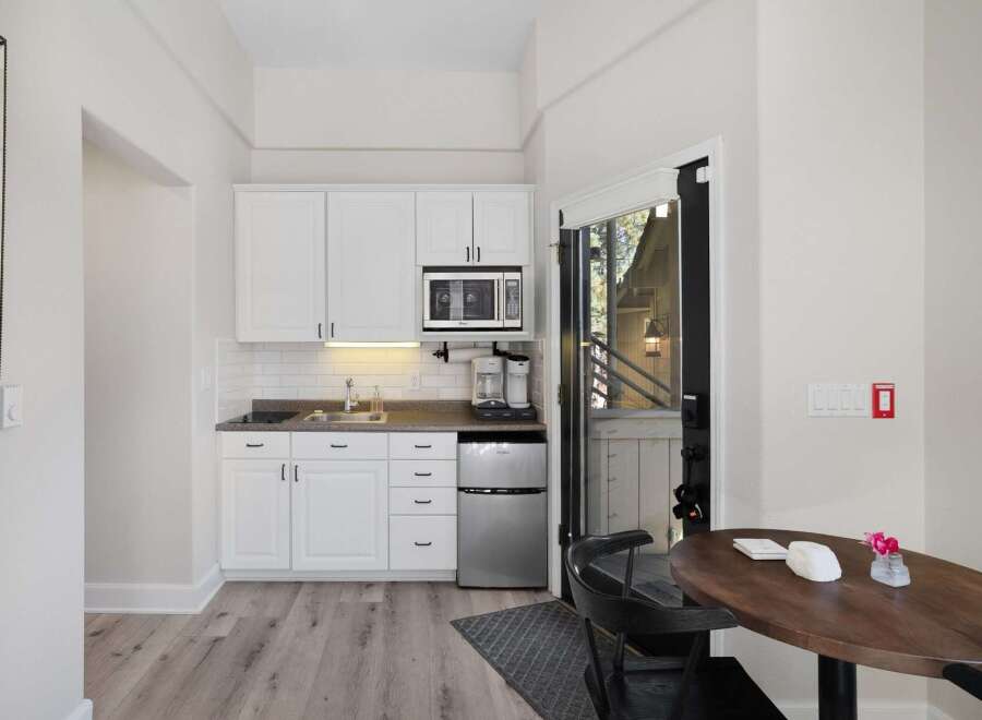 This charming studio features a compact yet fully equipped kitchenette with white cabinetry, a microwave, and a coffee maker, perfect for preparing simple meals.