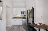 This charming studio features a compact yet fully equipped kitchenette with white cabinetry, a microwave, and a coffee maker, perfect for preparing simple meals.