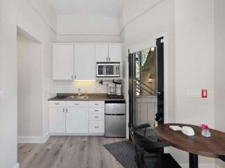 This charming studio features a compact yet fully equipped kitchenette with white cabinetry, a microwave, and a coffee maker, perfect for preparing simple meals.