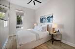 Experience serene comfort in this beautifully appointed bedroom, featuring a plush queen-size bed dressed in crisp white linens and accented with charming floral pillows.