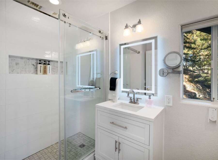 This modern bathroom features a sleek glass-enclosed shower with white subway tiles and a marble mosaic niche for toiletries.
