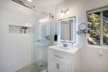 This modern bathroom features a sleek glass-enclosed shower with white subway tiles and a marble mosaic niche for toiletries.
