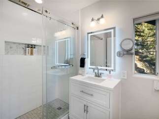 This modern bathroom features a sleek glass-enclosed shower with white subway tiles and a marble mosaic niche for toiletries.