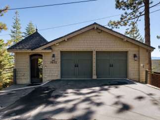 This charming property features a spacious two-car garage with classic dark green doors, perfect for protecting your vehicles.