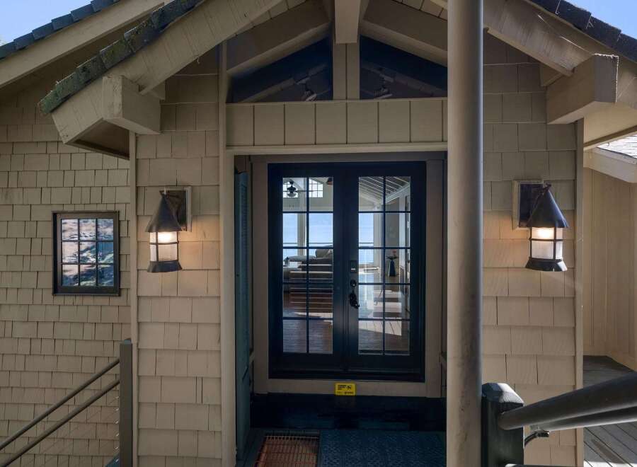 Welcome guests to your home with this charming entryway featuring a set of dark-framed double doors that open to a stunning view of the water.
