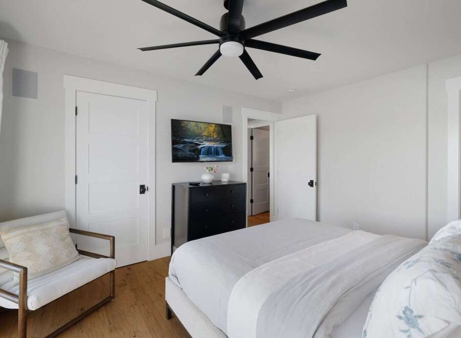 Experience modern comfort in this beautifully appointed bedroom, featuring a plush bed with crisp white linens and a stylish accent chair.