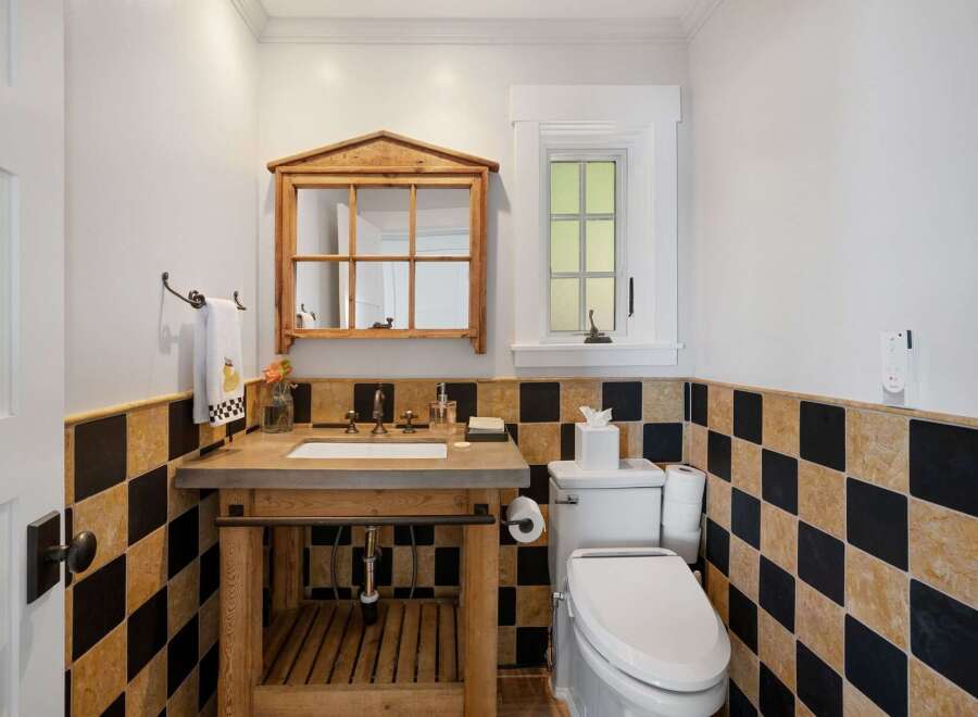 This charming bathroom features a rustic wooden vanity with a concrete countertop, complemented by a unique mirrored cabinet above.