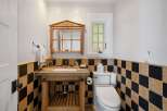This charming bathroom features a rustic wooden vanity with a concrete countertop, complemented by a unique mirrored cabinet above.
