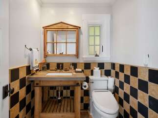 This charming bathroom features a rustic wooden vanity with a concrete countertop, complemented by a unique mirrored cabinet above.
