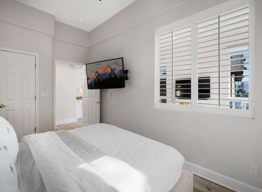 This bedroom offers a comfortable and modern retreat, featuring a plush white bed with a textured duvet and a decorative throw.