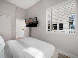 This bedroom offers a comfortable and modern retreat, featuring a plush white bed with a textured duvet and a decorative throw.