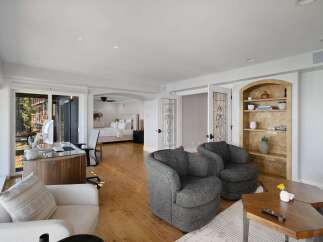 This spacious master suite offers a dedicated workspace with a modern desk and computer, overlooking a serene outdoor view.