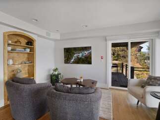 Experience breathtaking natural beauty from this living room, featuring a stunning aerial view of a river and forest displayed on a wall-mounted television.
